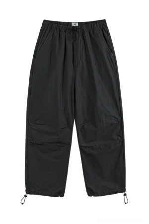 Black relaxed nylon-blend parachute pants with elastic drawstring waist and adjustable ankle cuffs front view