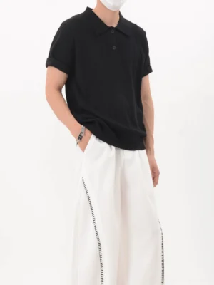 Black relaxed fit textured knit polo shirt with classic collar and rolled short sleeves styled in a minimalist streetwear outfit
