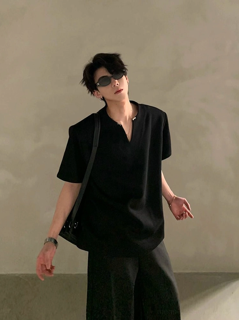 Black relaxed silhouette V-notch neck short sleeve shirt shown from the side with natural folds and a modern urban outfit