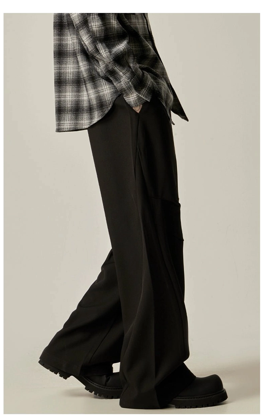 Black relaxed wide-leg cargo trousers shown in motion with side utility pockets, clean matte fabric, and black boots