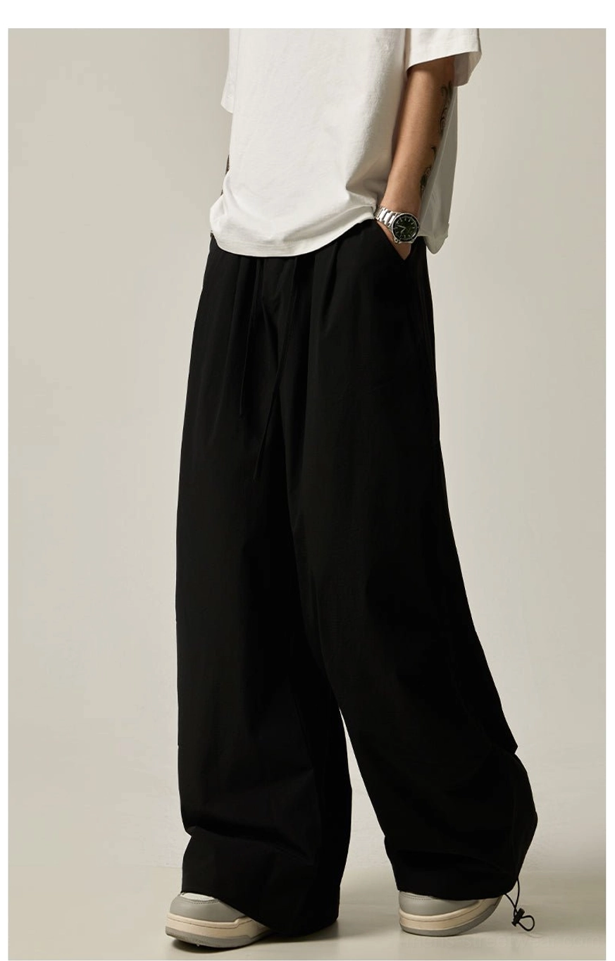Black relaxed wide leg pants for men styled with a white T-shirt and subtle ankle drawstring details