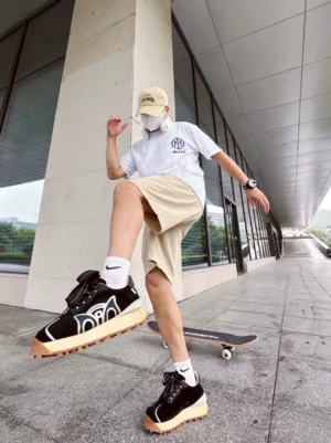Black retro runner sneakers worn by a male street skater in a modern outdoor corridor with casual Seoul-inspired streetwear styling
