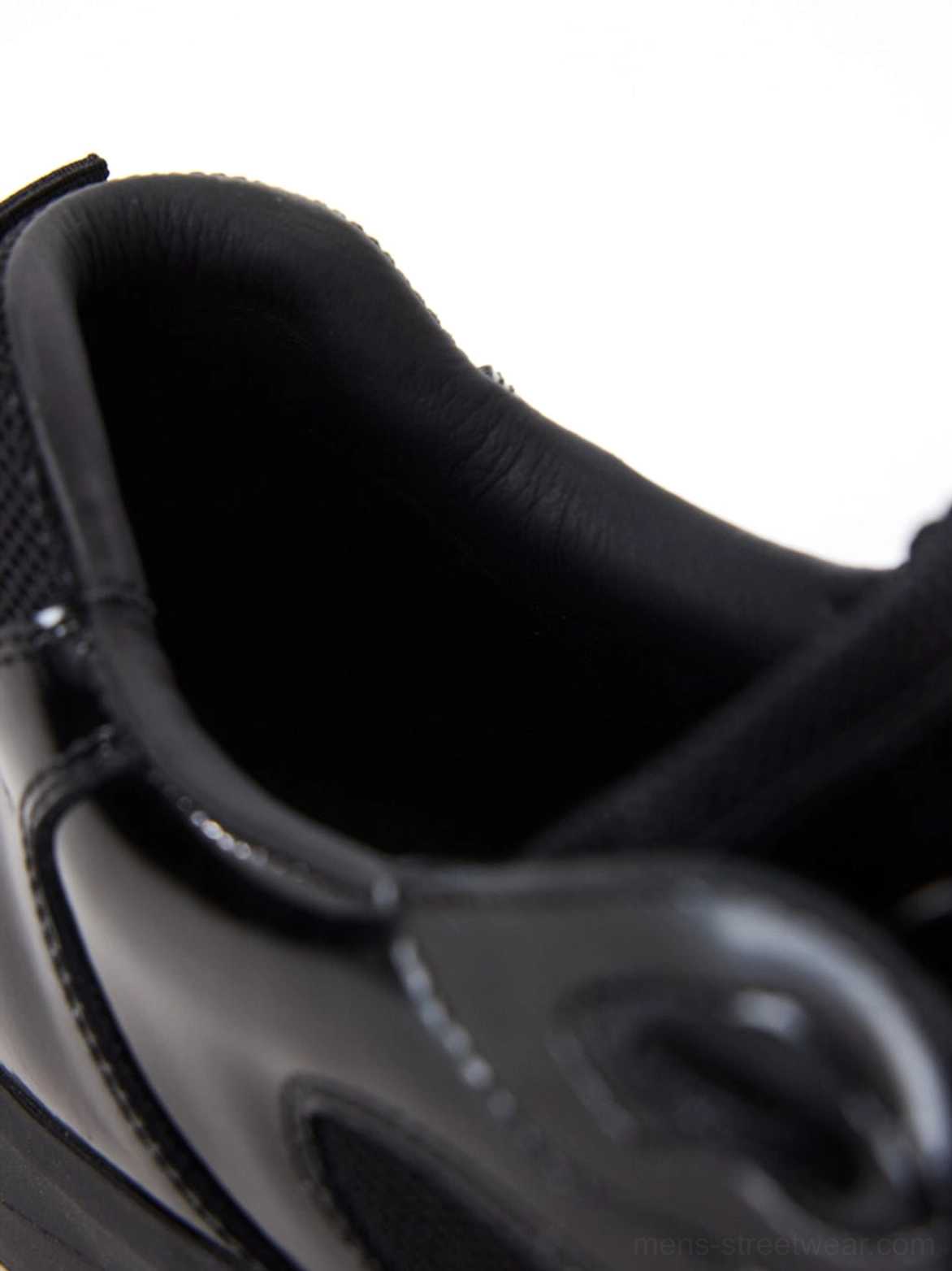 Close-up interior view of black retro runner sneakers showing soft leather lining padded mesh collar and precise topstitching