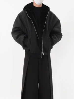 Black reversible faux fur lined oversized zip-up bomber jacket front three-quarter view with smooth matte outer shell