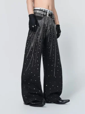 Rear three-quarter view of black rhinestone embellished wide-leg jeans with cascading silver starburst details, studded belt, and stacked streetwear silhouette