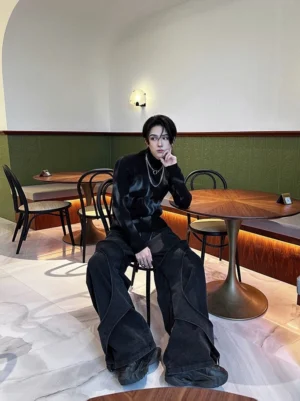 Front view of black ribbed turtleneck sweater with abstract grey washed pattern styled with silver chain necklaces and wide-leg jeans