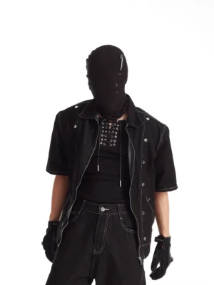 Close-up of black short sleeve rivet denim jacket with metal stud details layered over a lace-up tank top