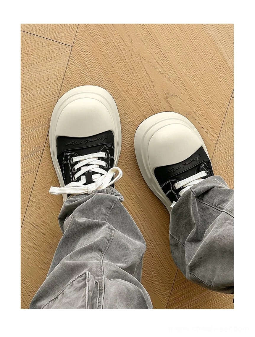 Overhead wearing view of black round toe platform sneakers styled with grey cargo pants, highlighting the height-increasing sole and Seoul streetwear silhouette