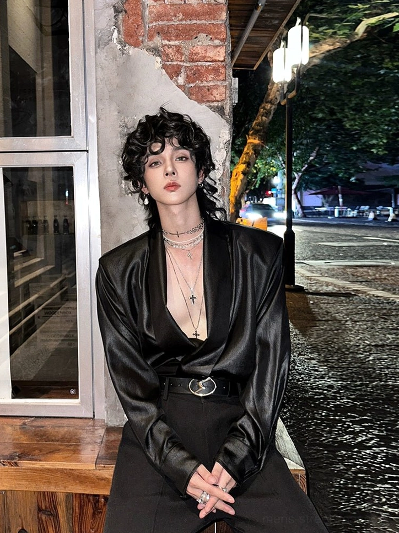 Black satin deep V-neck shirt styled on a male model at night with an oversized silhouette and circular buckle belt