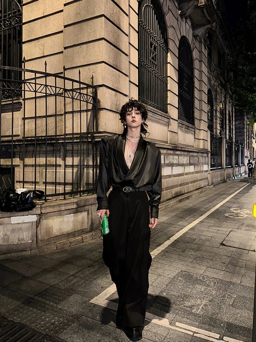 Black satin deep V-neck shirt with structured shoulders styled with a black belt and wide-leg trousers