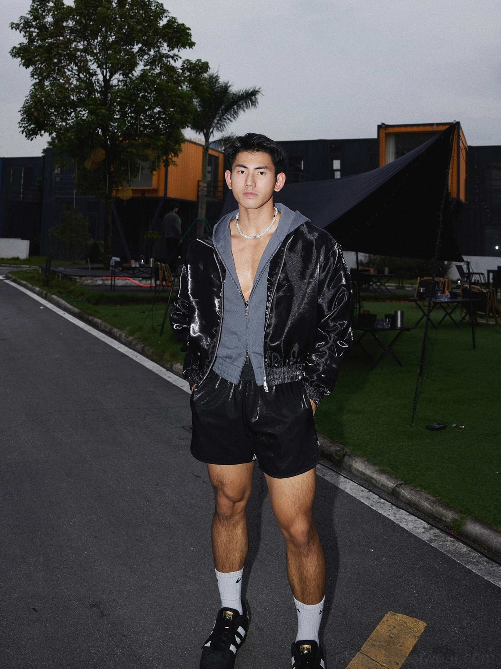 Three-quarter front view of minimalist black satin shorts with loose boxer-style streetwear silhouette