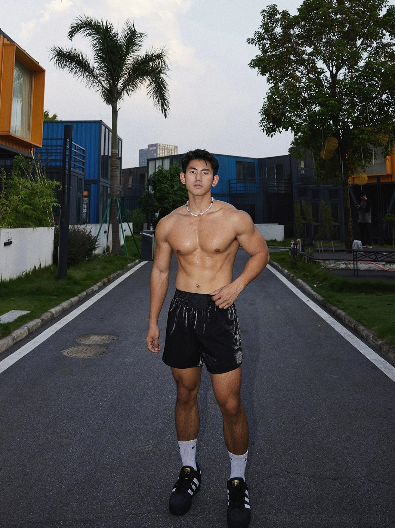 Three-quarter view of relaxed black satin athletic shorts in a Korean-inspired summer streetwear outfit