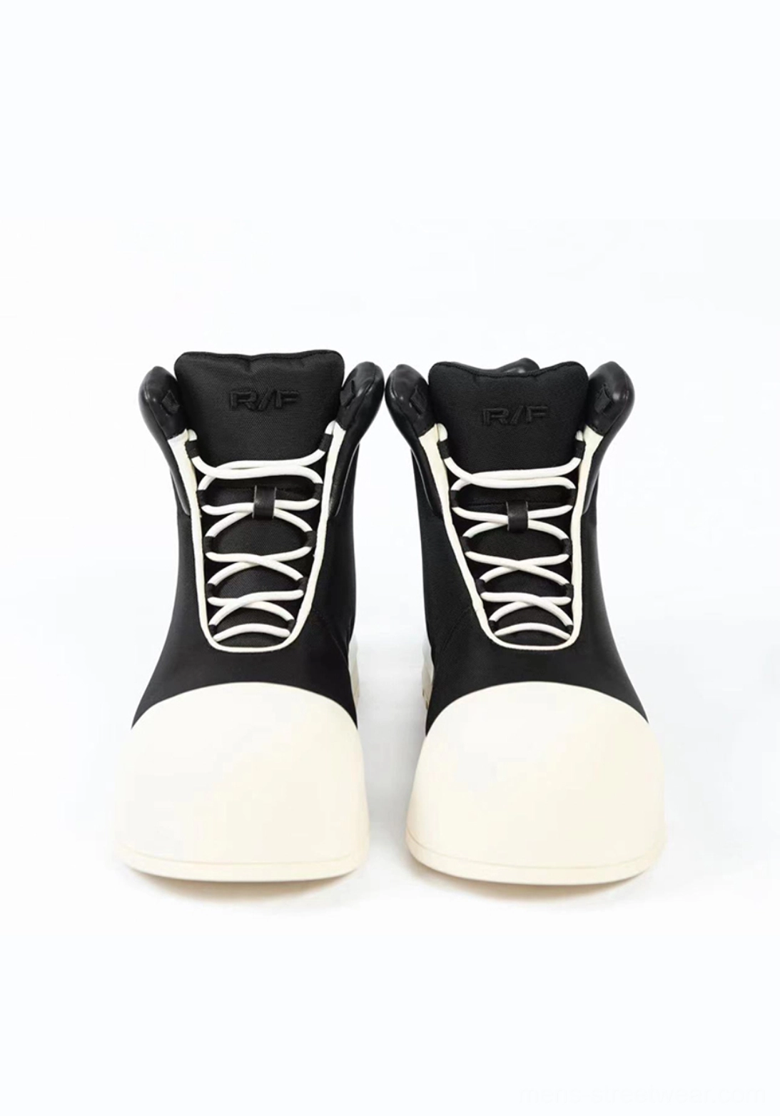Front view of black sculpted-toe platform high-top boots with white laces, padded collars, and contrast toe caps