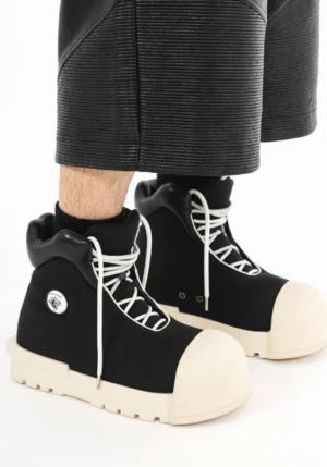 Black sculpted-toe platform high-top boots worn with cropped black pants in an avant-garde streetwear outfit