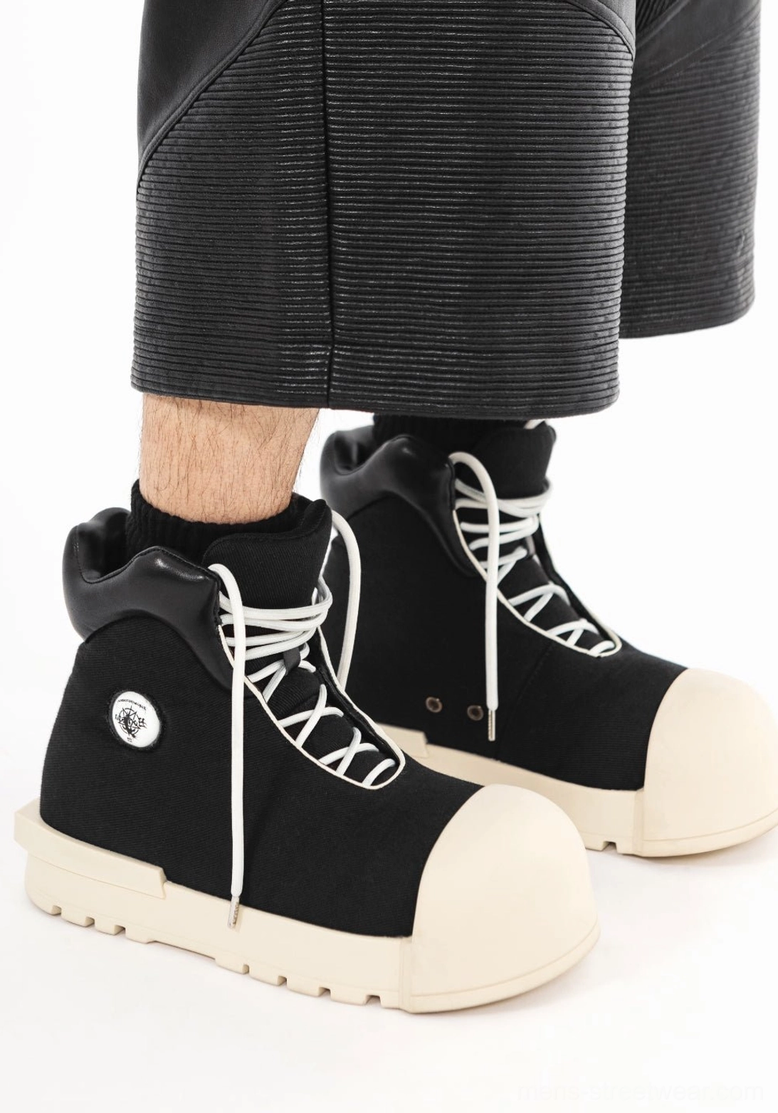Black sculpted-toe platform high-top boots worn with cropped black pants in an avant-garde streetwear outfit