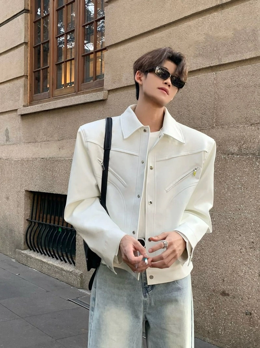 Black sculpted wide-shoulder streetwear jacket styled with dark wide-leg jeans and a silver chain necklace