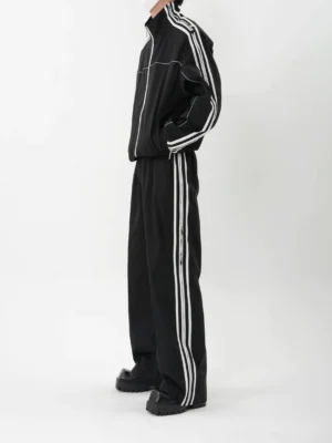 Side view of black Korean streetwear tracksuit with shoulder stripe jacket and wide-leg pants with dual side stripes