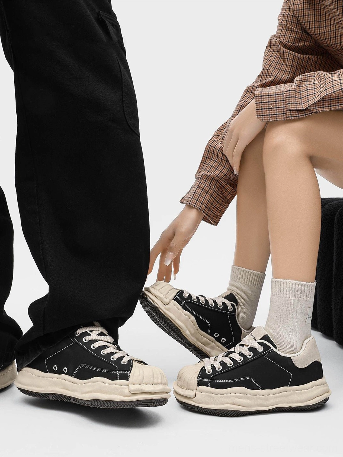 Two people wearing black shell-toe platform sneakers with different everyday trousers, highlighting the lifted sole and versatile fit
