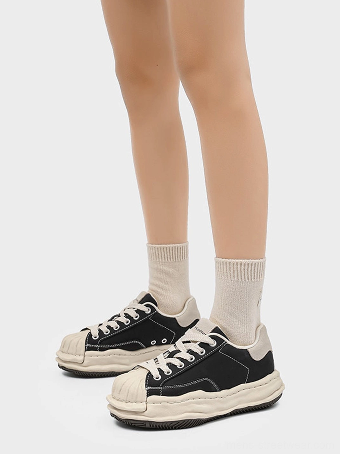 Pair of black shell-toe platform sneakers displayed from front and side angles to show the beige toe contrast and stacked sole
