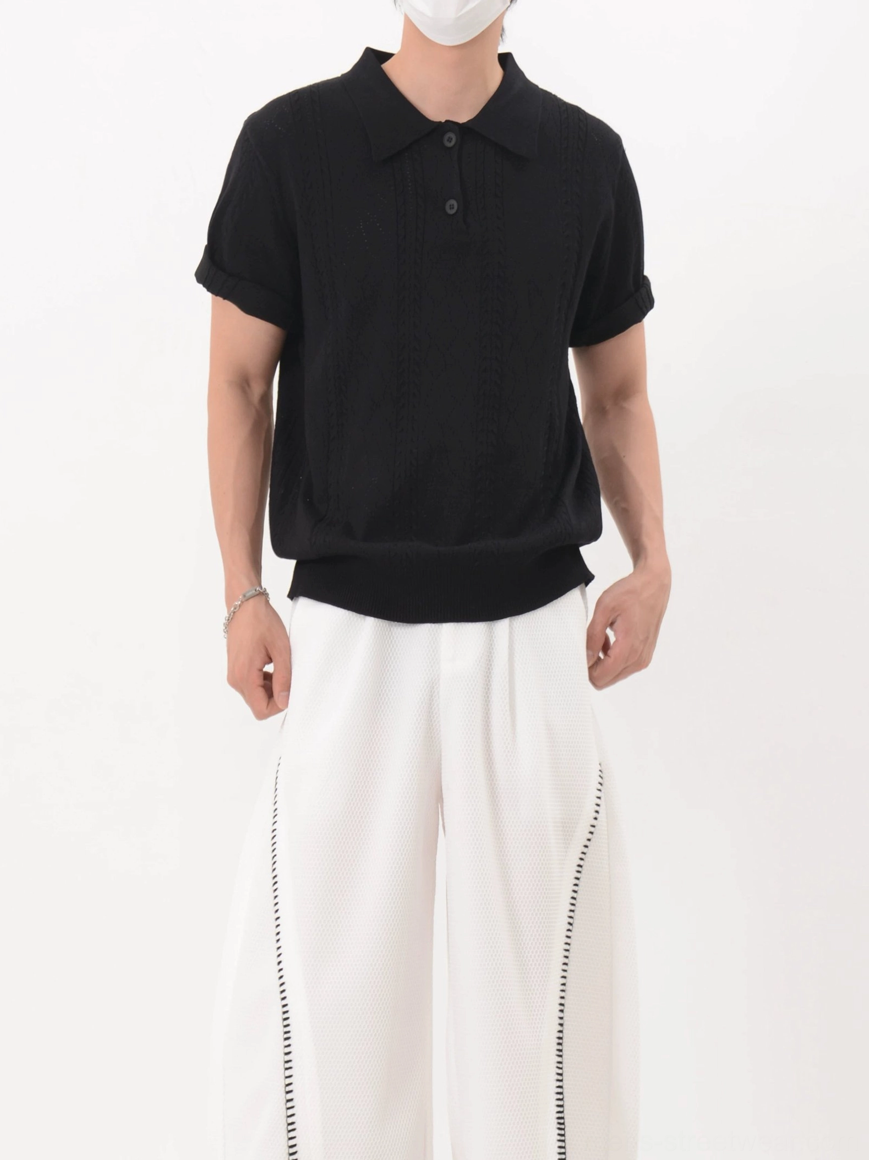 Black short sleeve textured lattice knit polo shirt with relaxed boxy silhouette styled with white wide-leg trousers