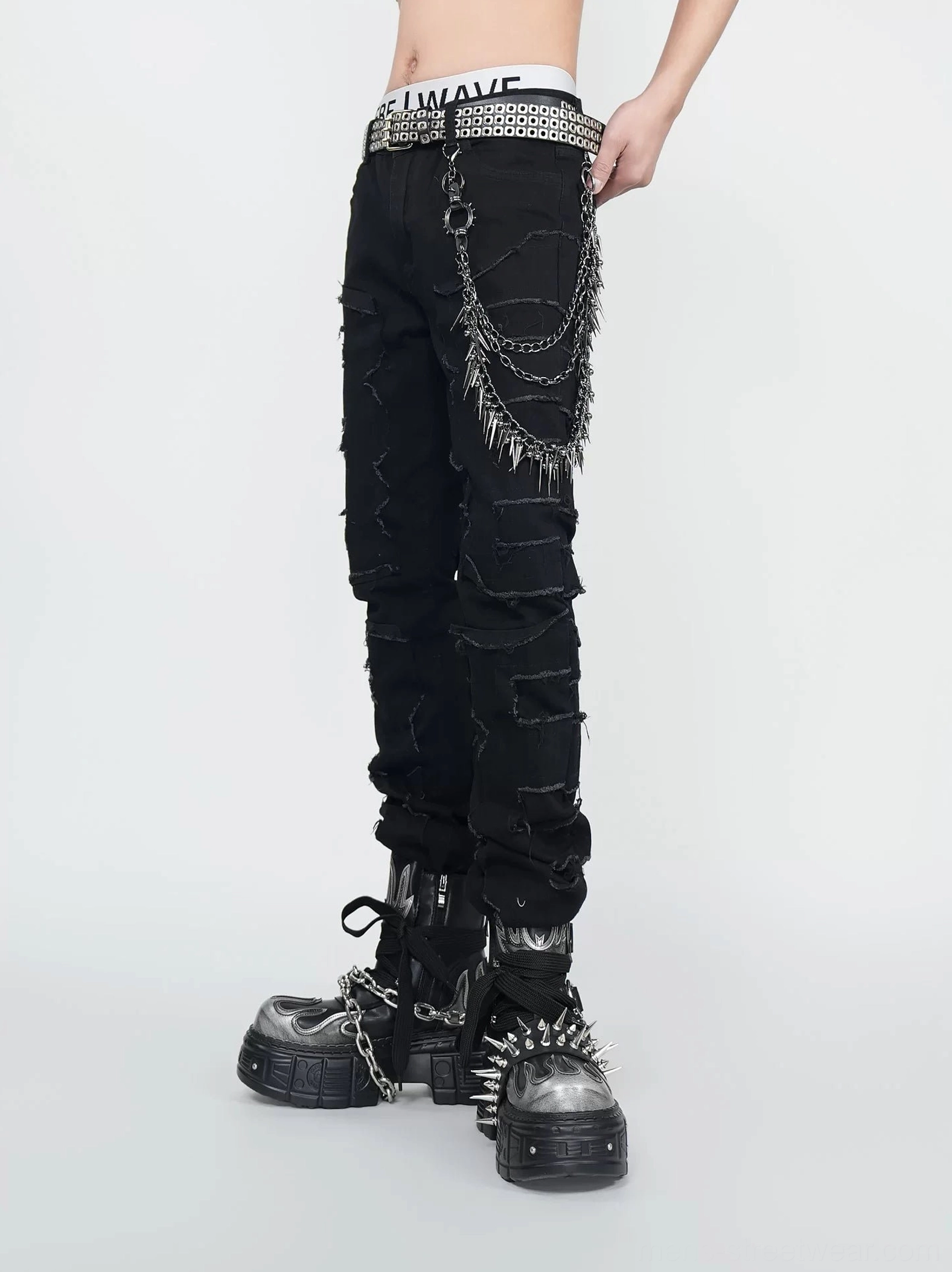 Close front view of black shredded punk jeans showing frayed denim texture, layered spiked hip chain, non-elastic waist, and chunky platform boots