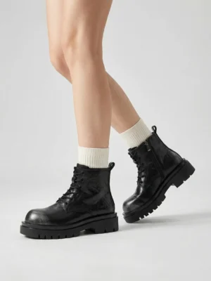 Black side-zip lace-up platform lug sole combat boots worn with white crew socks in a low front outfit view