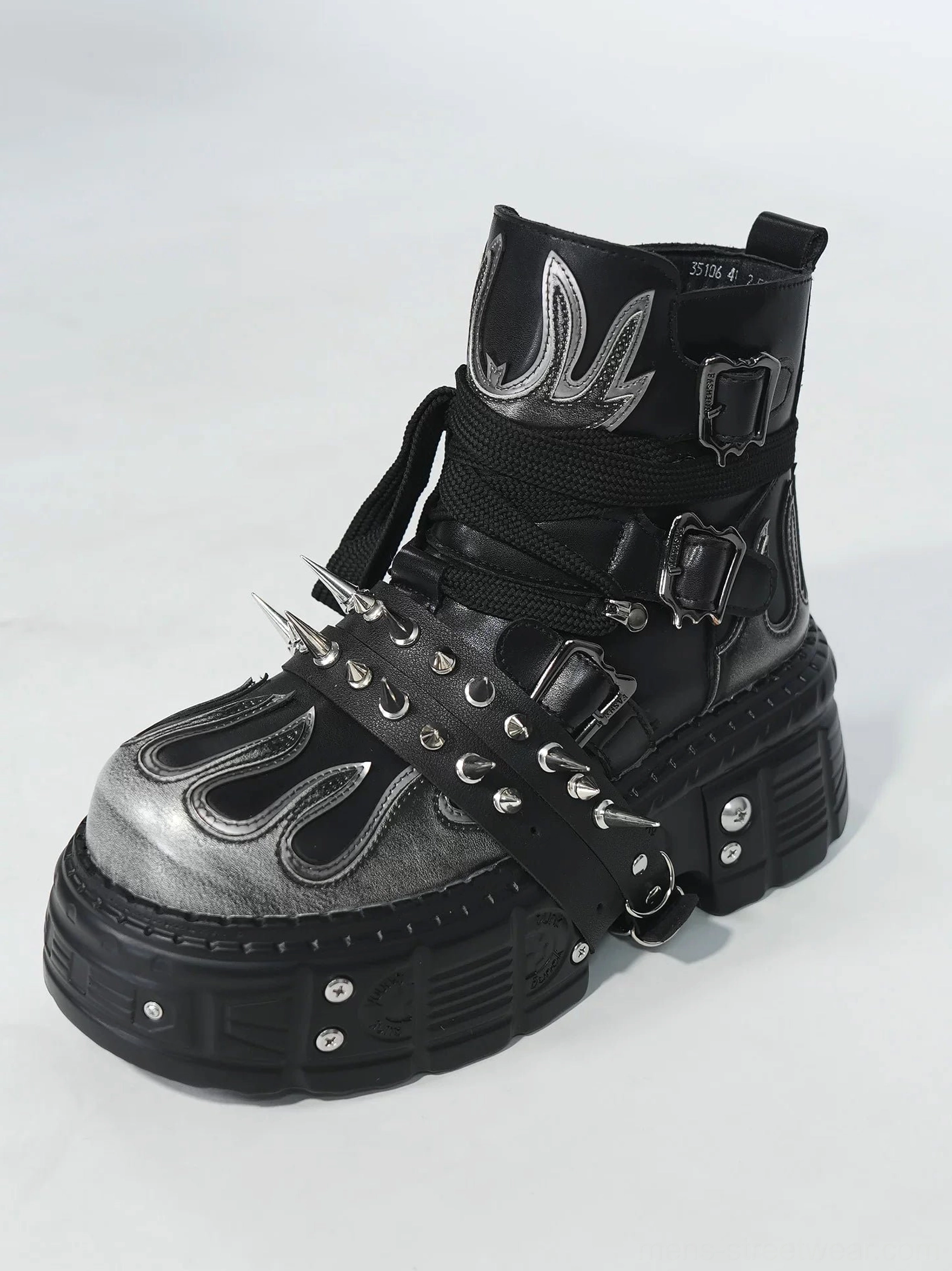 Side view of black and silver flame platform boot with spike studded buckle strap decorative ankle detail and chunky lug outsole