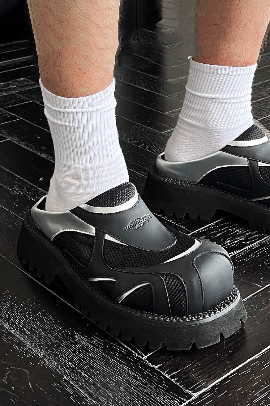 On-foot view of black and silver mesh platform loafers worn with white crew socks and a chunky lug sole
