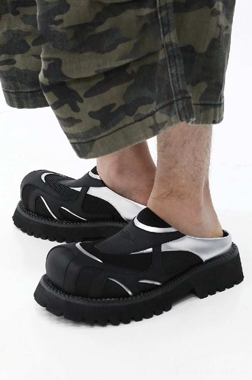Low-angle view of black silver mesh platform slip-ons styled with camo cargo shorts and a durable lug outsole