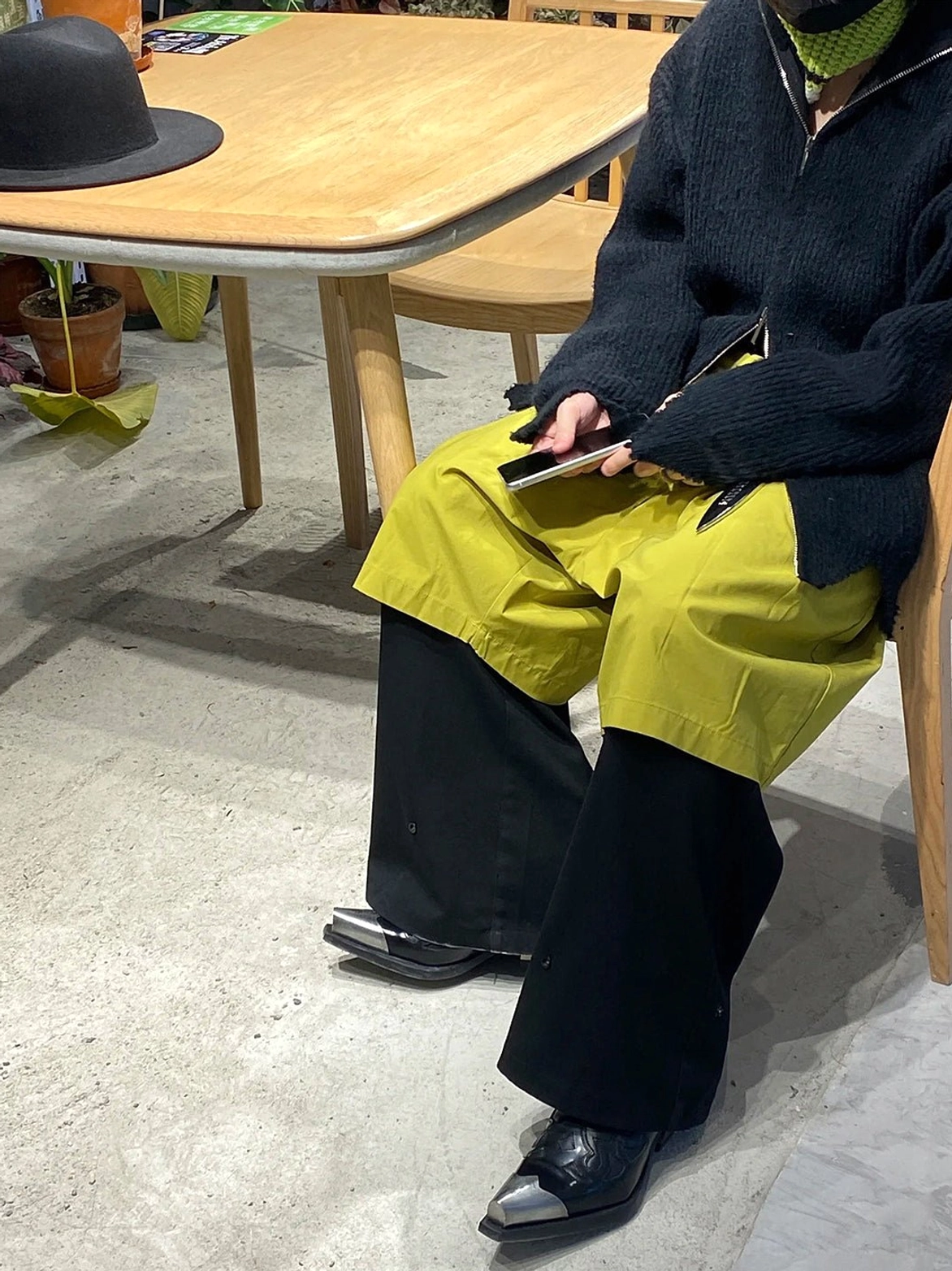 Black silver toe heeled Chelsea boots worn with two-tone wide leg pants in an indoor streetwear styling scene