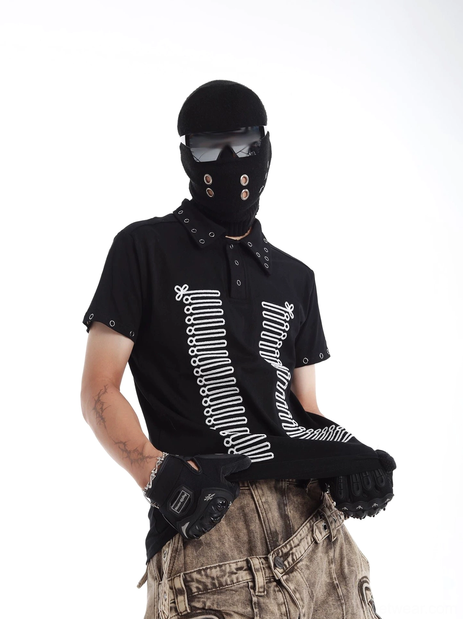 Black skeleton graphic polo shirt with symmetrical spine print, metal eyelet rivets on collar and sleeves, styled with camo cargo pants in Korean techwear streetwear fashion