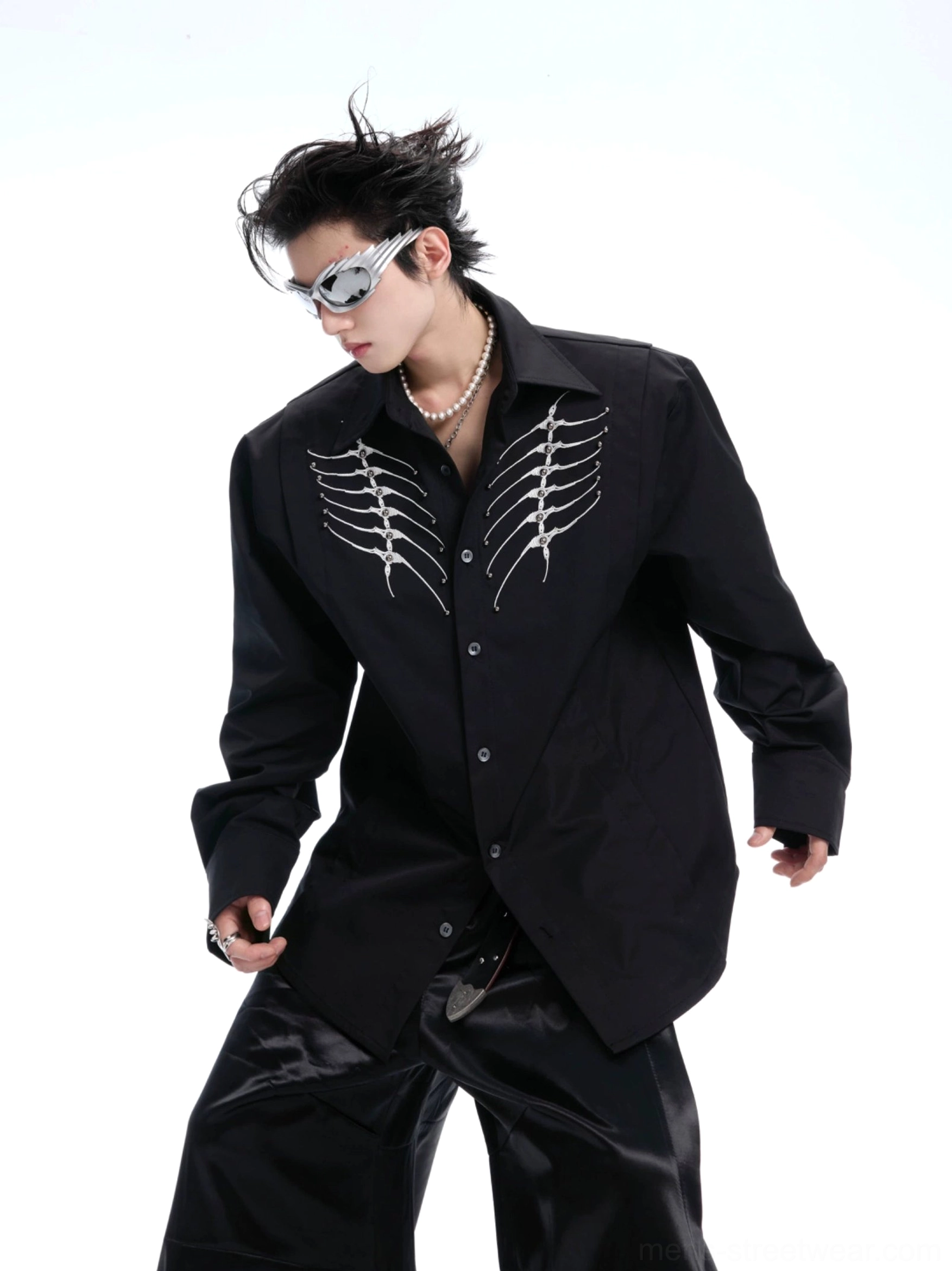 Black ribcage embroidered button-up shirt styled with shiny wide-leg trousers and silver avant-garde accessories