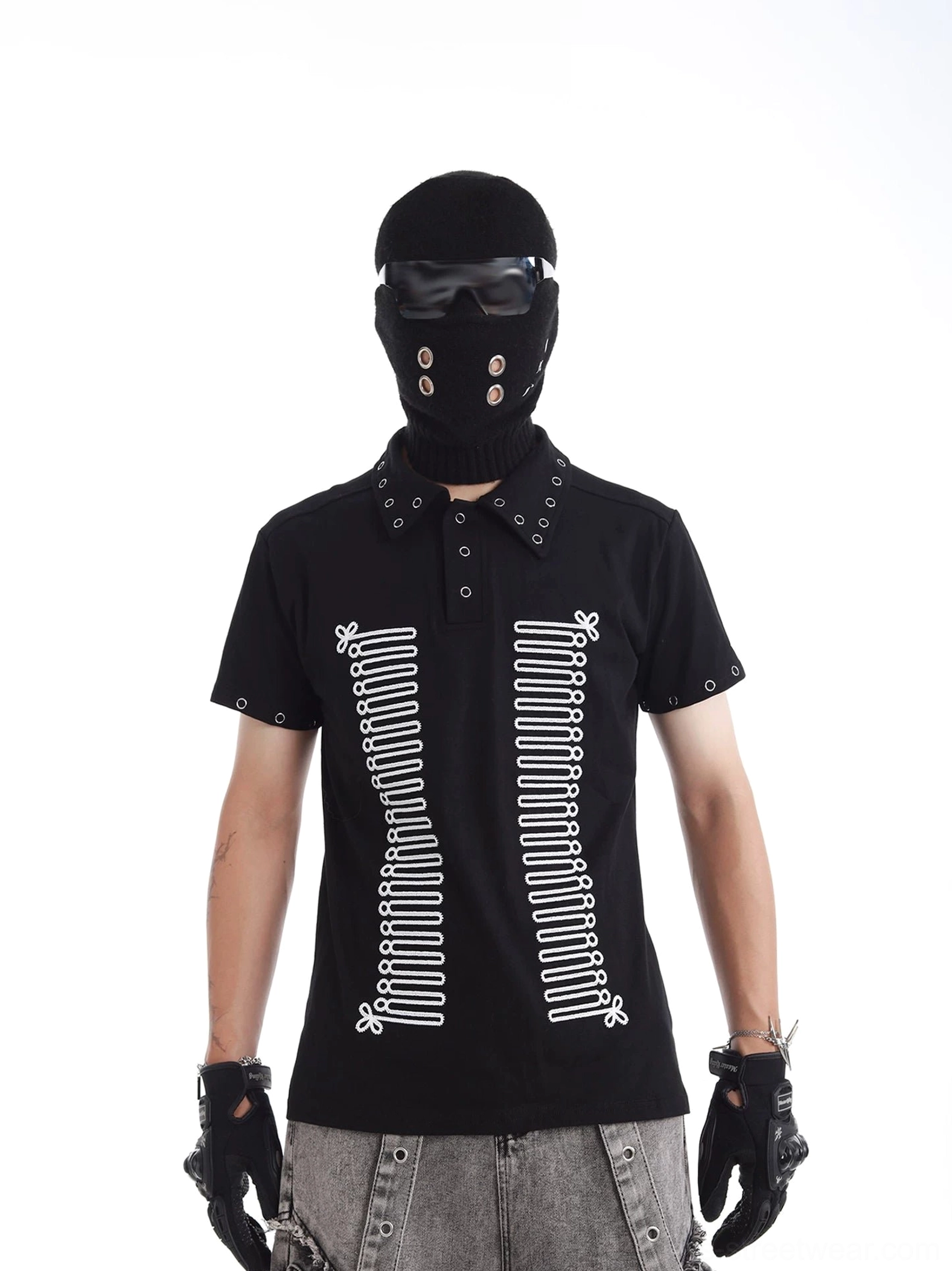 Front view of black rivet-accented skeleton polo shirt with symmetrical bone print, metal collar eyelets, and short sleeve hardware styled with grey washed denim