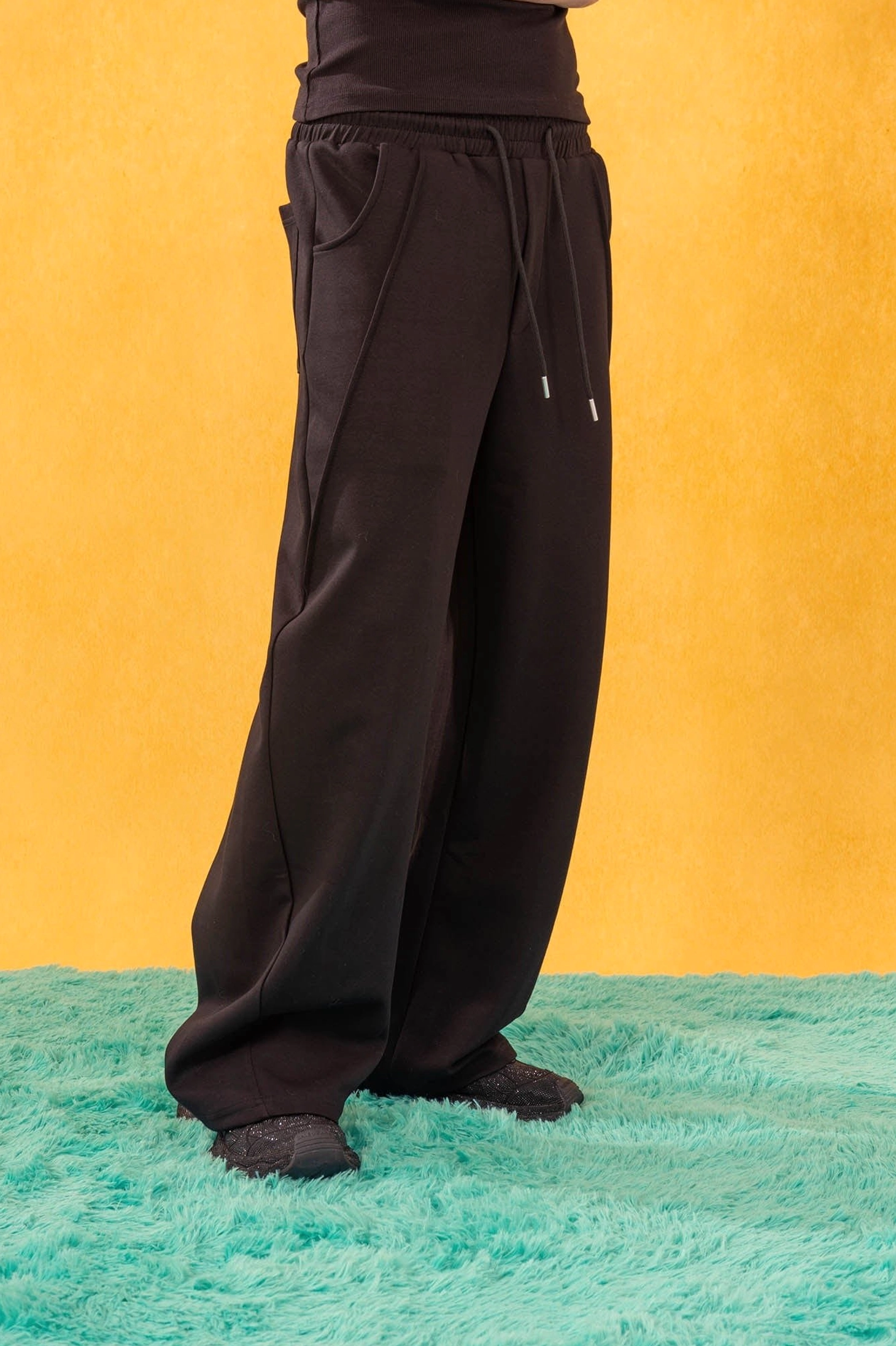Black slanted spliced wide-leg sweatpants shown from the front side with curved seam and side slit pockets
