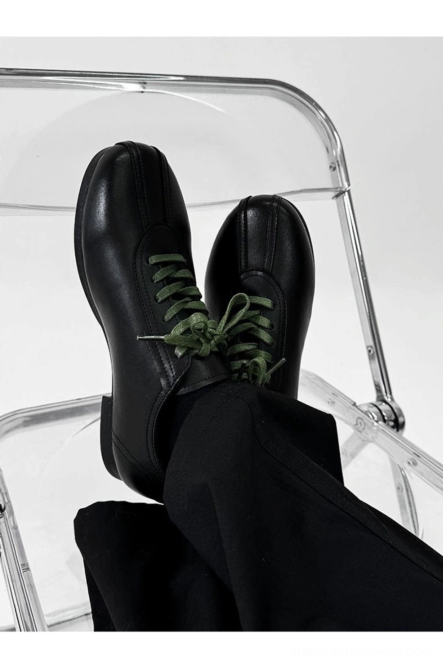Black split-toe derby shoes featuring green contrast shoelaces, clean derby construction, and contemporary Asian streetwear style