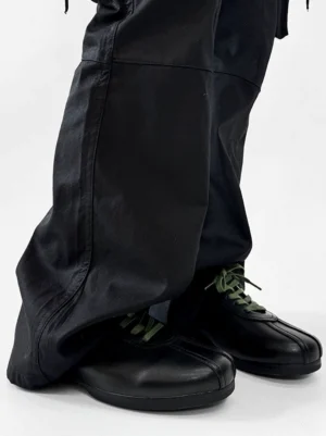 Side view of black split-toe derby shoes with polished synthetic leather finish, green laces, and streamlined derby silhouette
