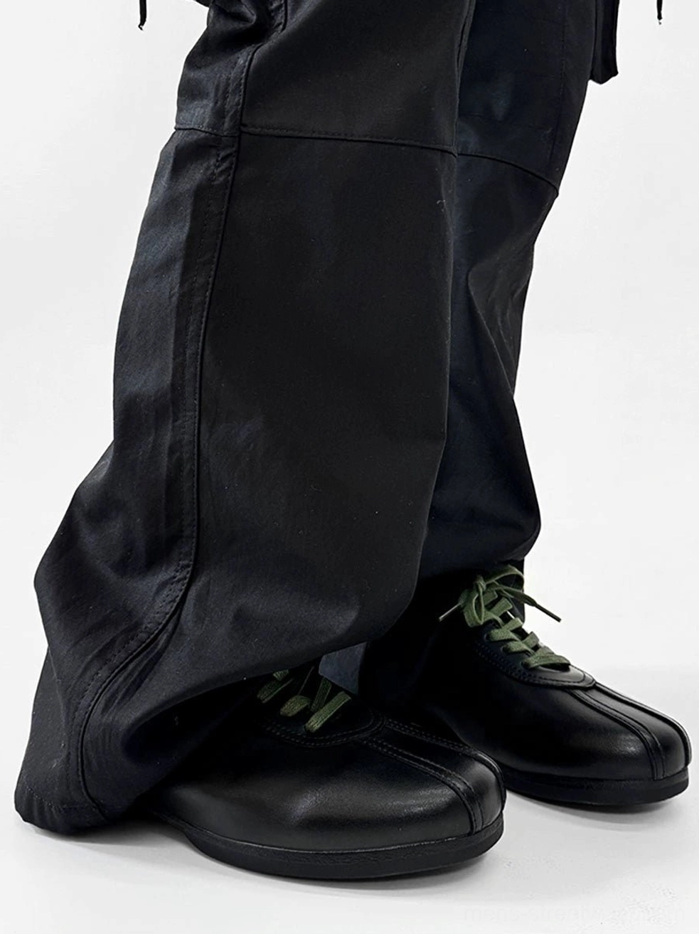 Side view of black split-toe derby shoes with polished synthetic leather finish, green laces, and streamlined derby silhouette