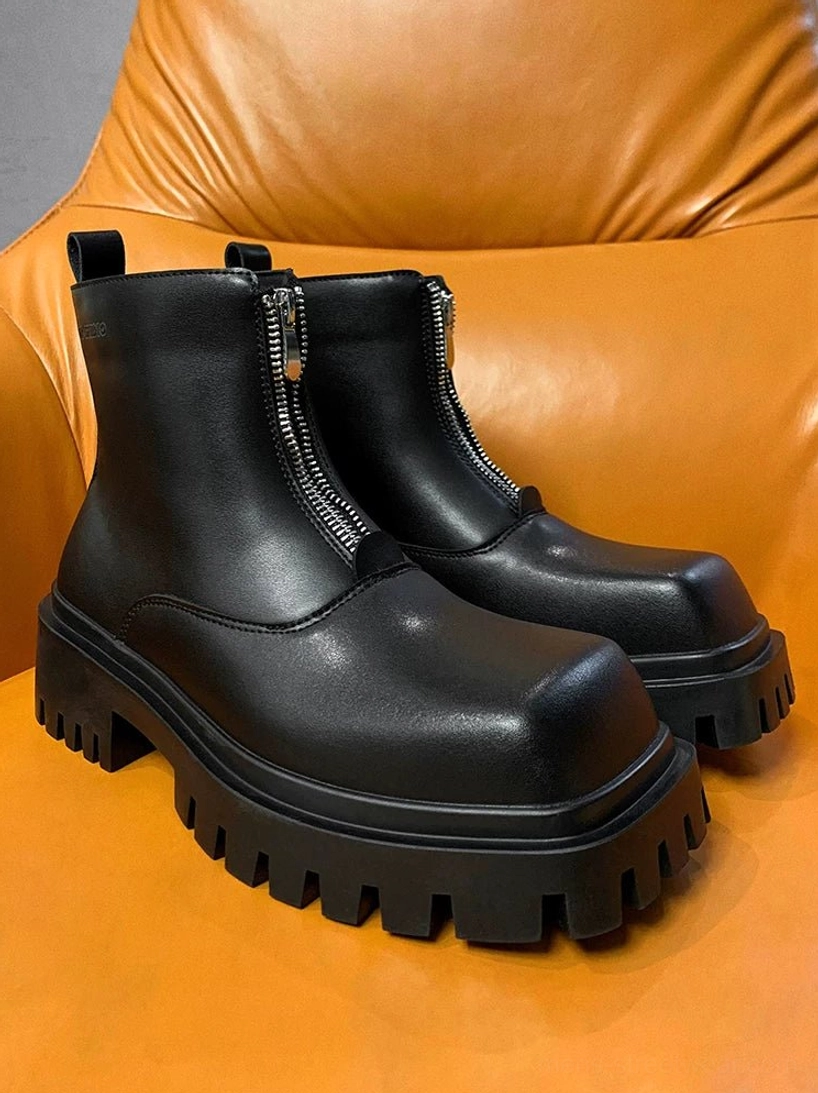 Three-quarter view of black square-toe front-zip platform boots showing the raised heel and thick industrial lug outsole