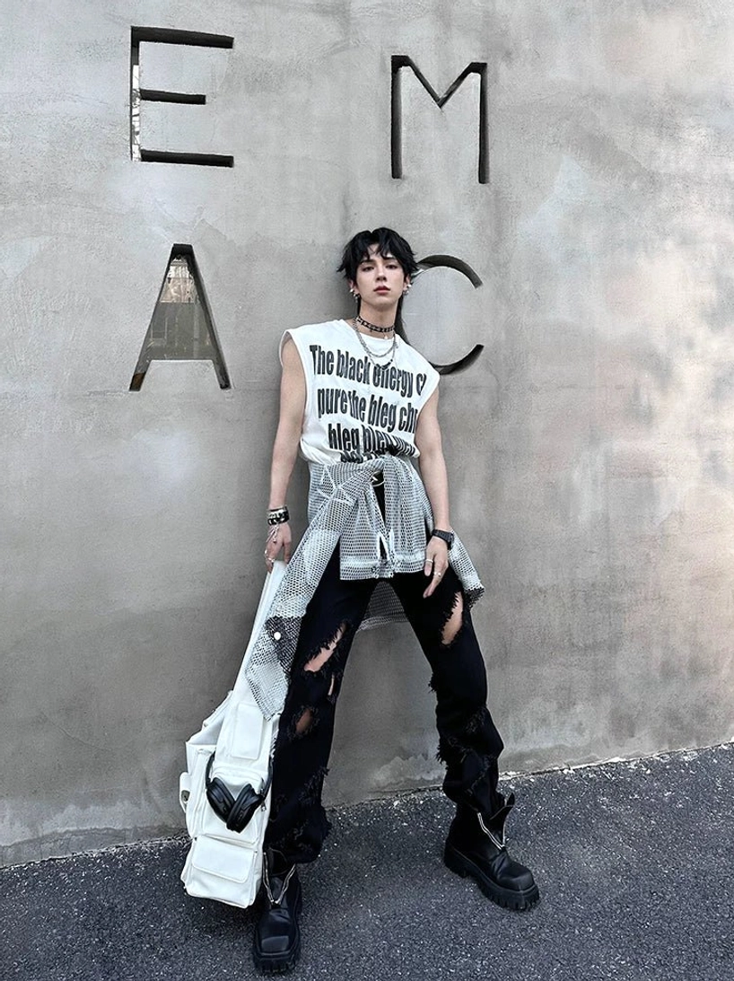 Androgynous streetwear model wearing black square-toe platform boots with ripped jeans, graphic tank top, cropped shirt, and shoulder bag