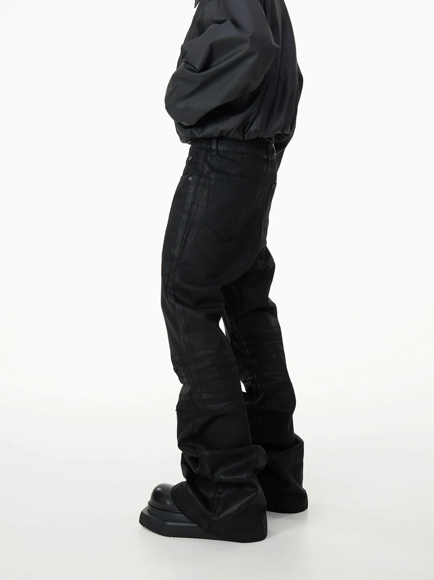 Left side profile of black stacked panel jeans with high waist, subtle thigh seam, and flared hems over platform shoes