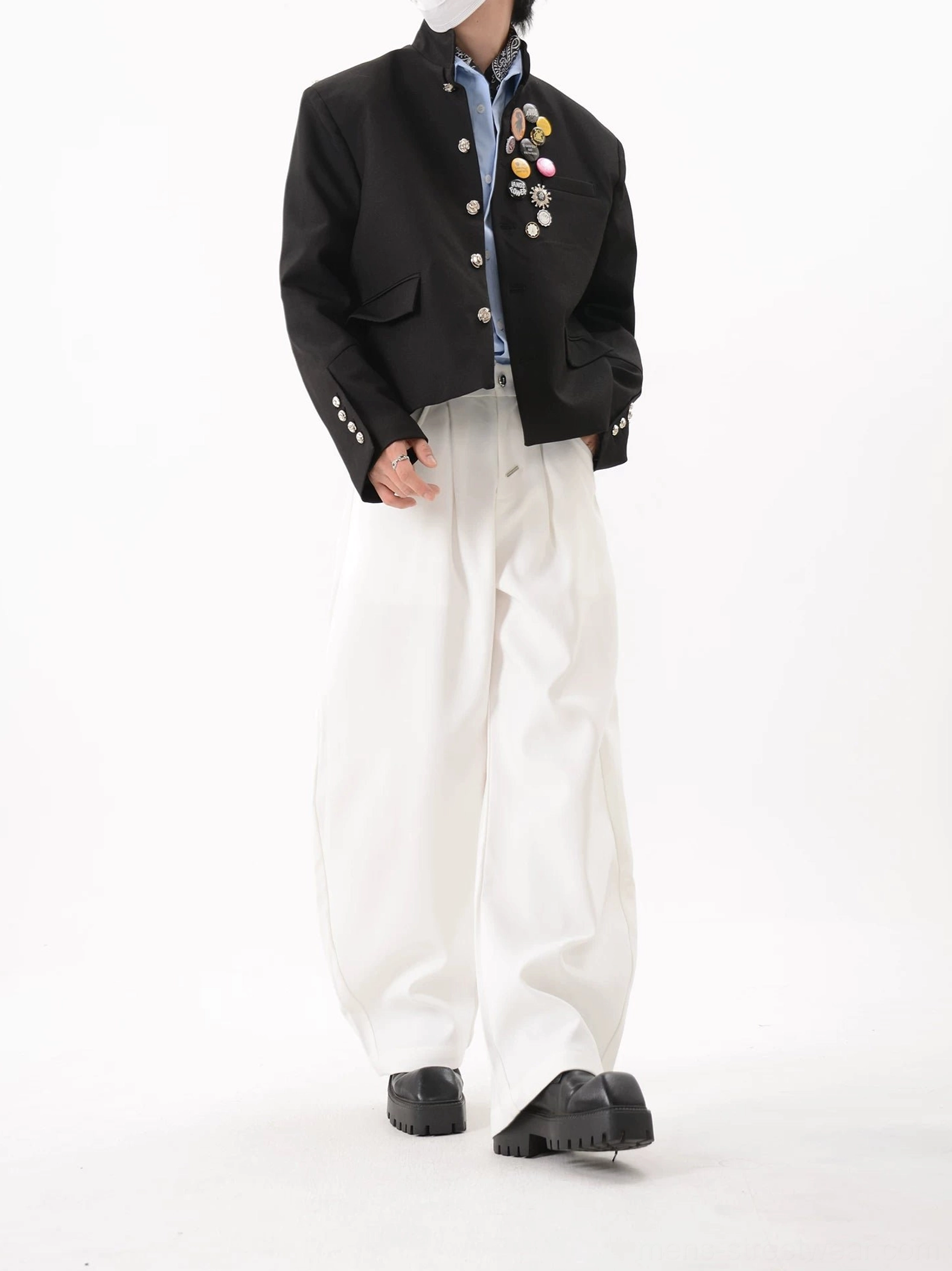 Black stand collar cropped streetwear blazer in right three-quarter view highlighting tailored shoulders and decorative crest brooches