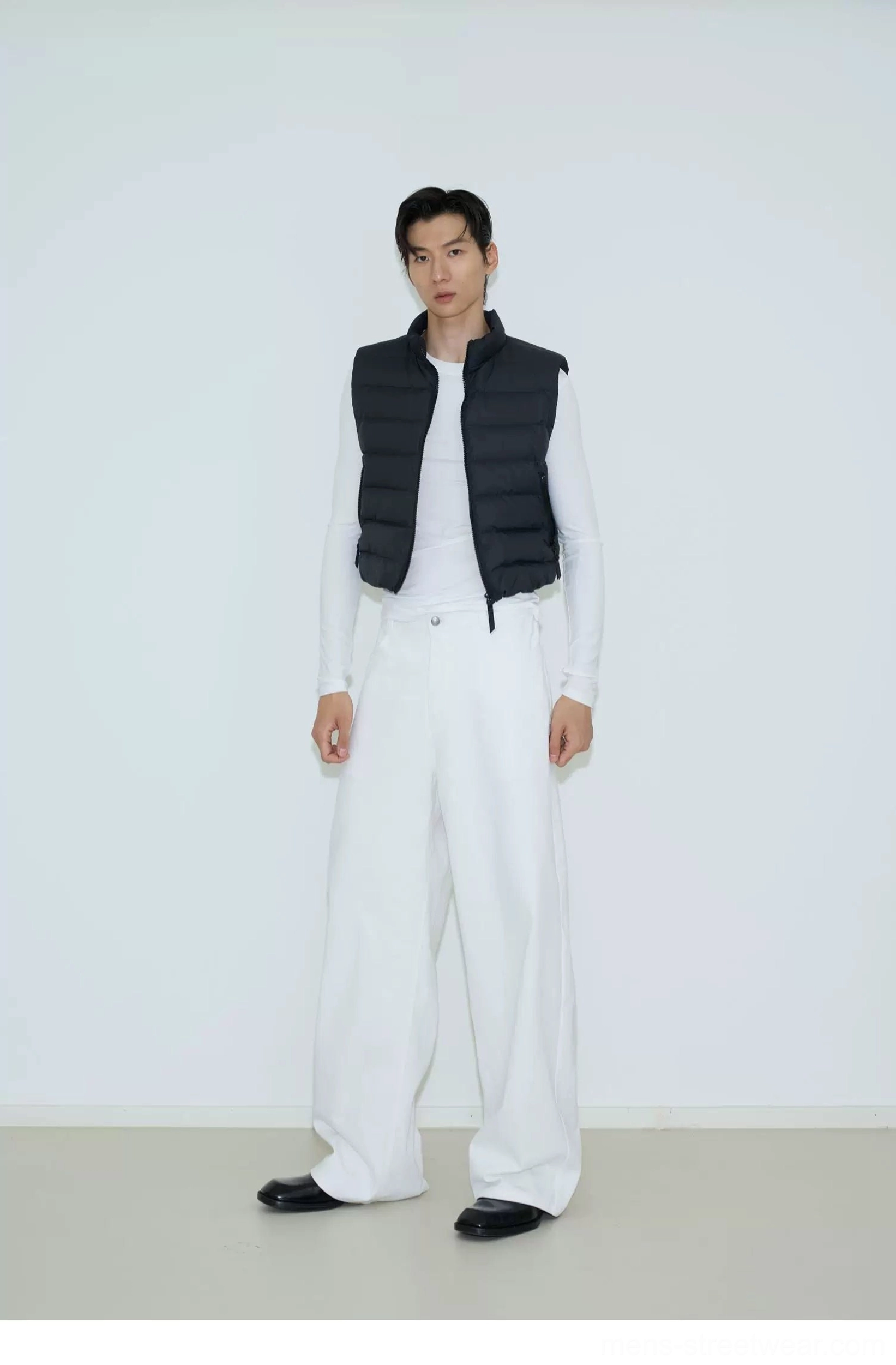 Black stand collar quilted puffer vest styled with a white base layer and wide leg trousers