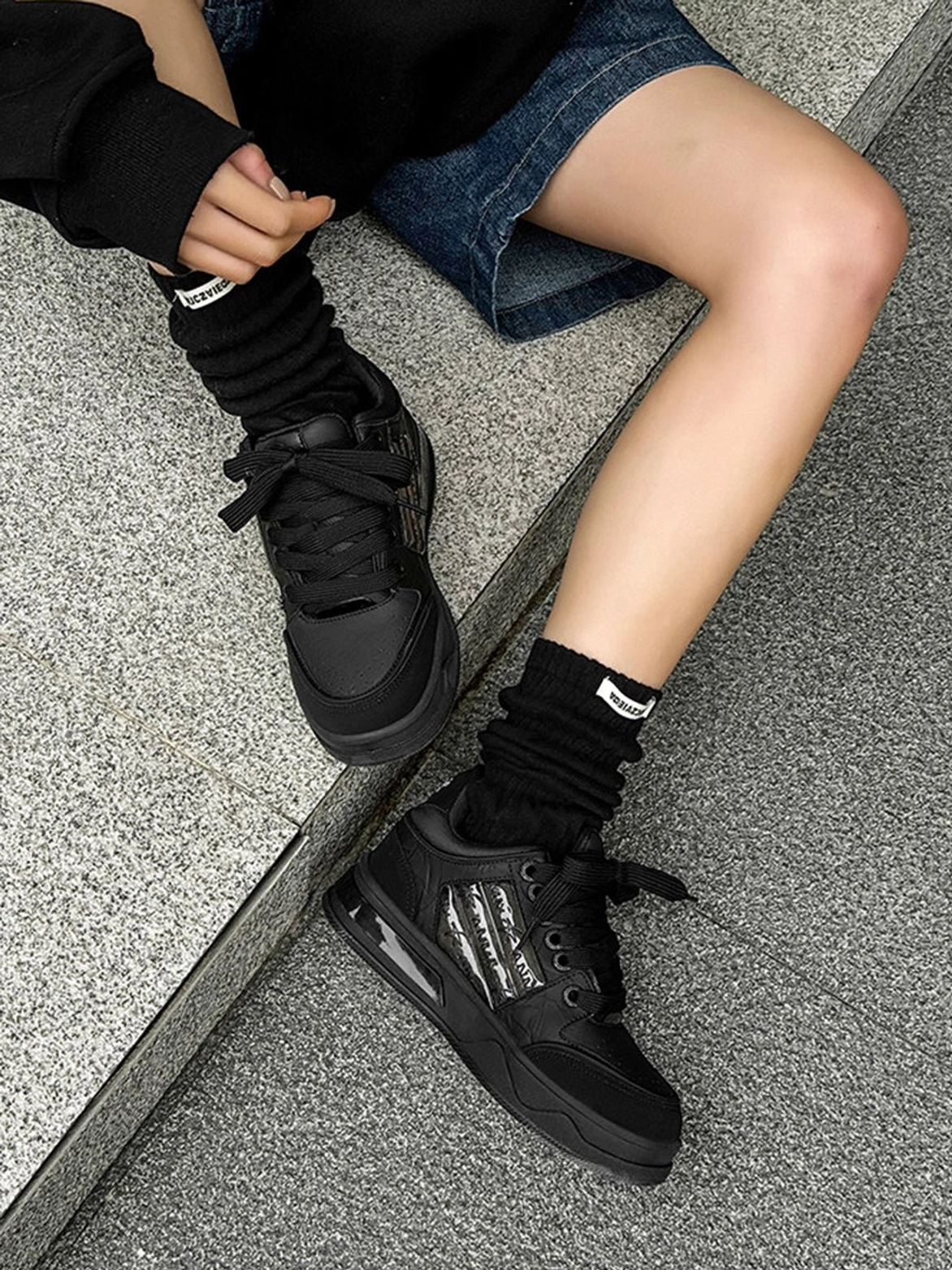 Black star studded gothic sneakers with lace-up closure, silver side accents, and chunky rubber soles in a streetwear outfit