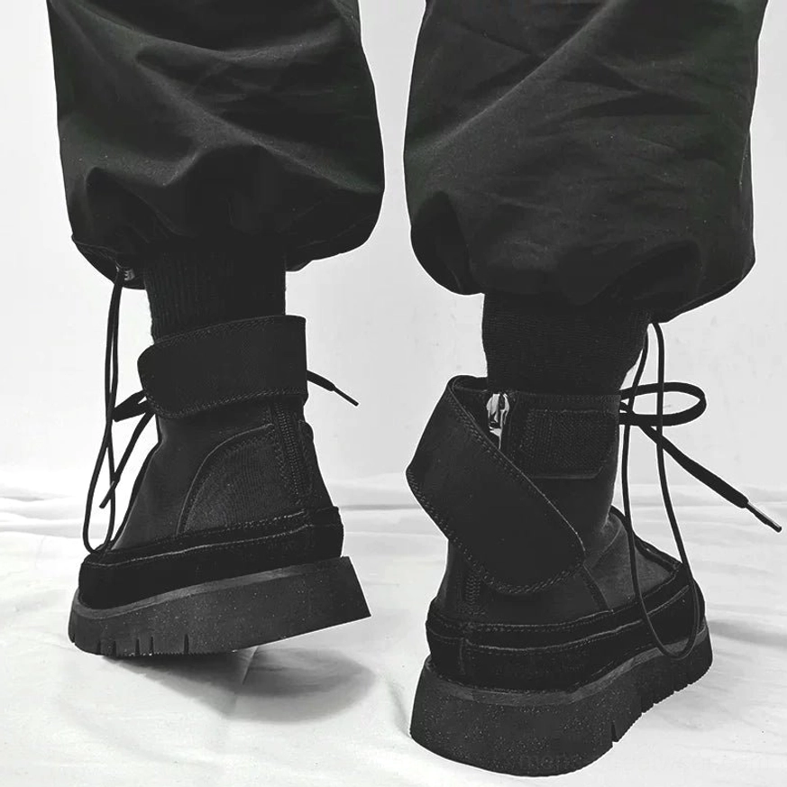 Rear side view of black Japanese streetwear boots showing heel strap, tied laces, high-top shaft, and thick rubber outsole