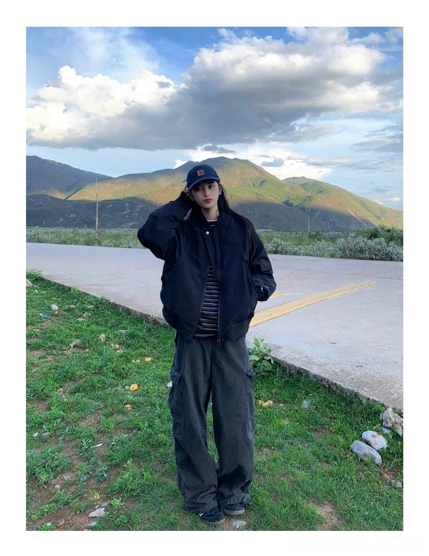 Black streetwear flight bomber jacket side view with striped shirt and wide-leg cargo pants at dusk