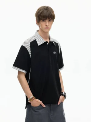 Male model wearing a black striped panel polo shirt with retro sport trim and relaxed boxy Seoul streetwear silhouette