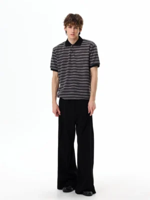 Full-body view of a relaxed black striped polo shirt with contrast trim and wide-leg trousers in a minimalist East Asian fashion look
