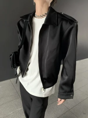 Black structured shoulder satin bomber jacket close-up showing padded shoulders, smooth fabric, cropped Seoul streetwear silhouette, and front zipper