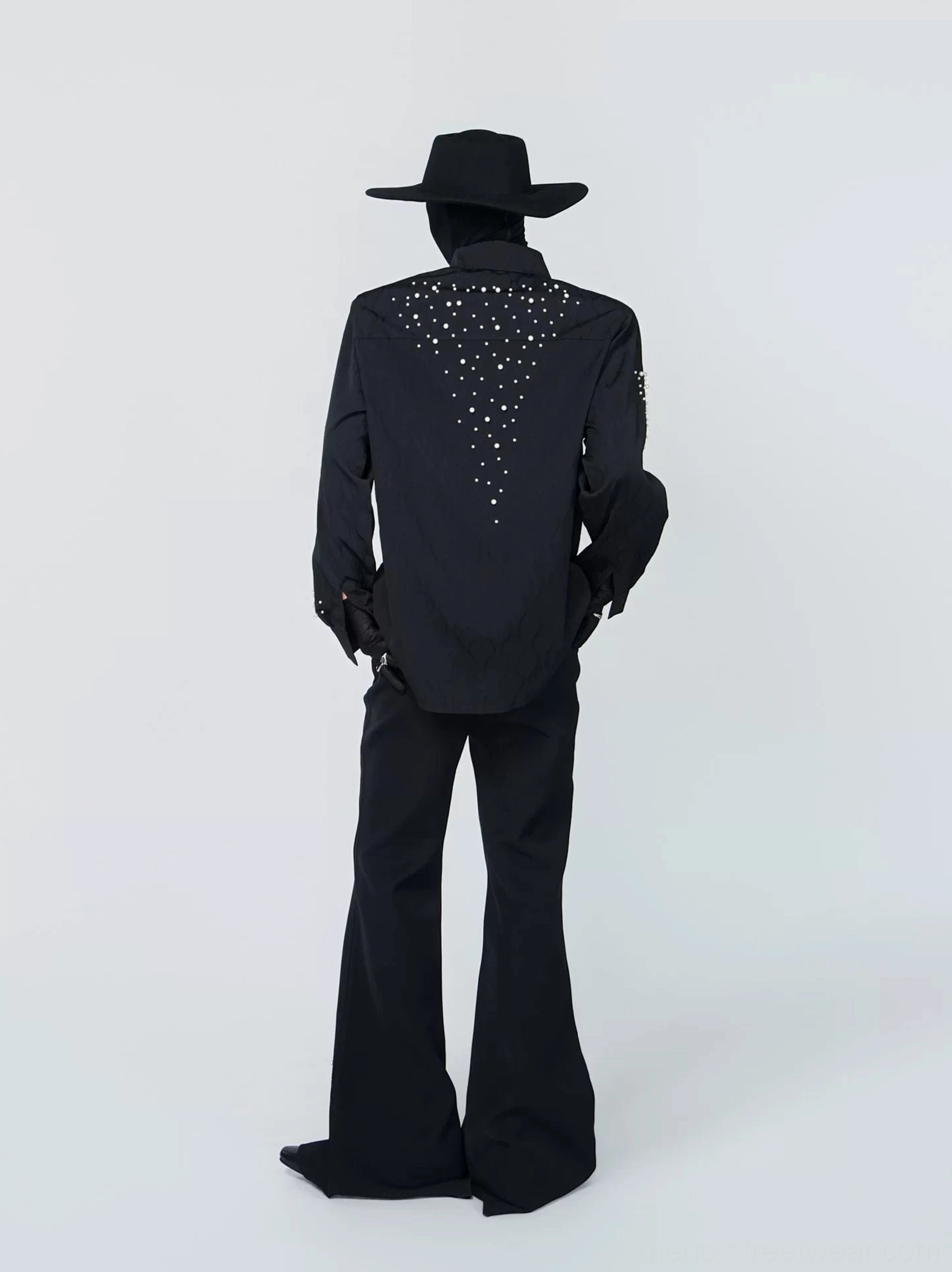 Rear view of a black studded constellation shirt showing star-like rhinestone embellishments spreading across the upper back and relaxed shoulder silhouette