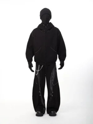 Black studded full-zip hoodie worn in a complete dark streetwear outfit with wide-leg pants, beanie, gloves, and silver hardware details